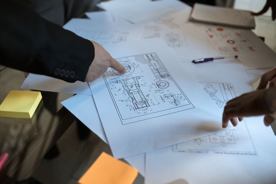 Engineers discussing blueprints at a workspace, focusing on teamwork and architecture design.